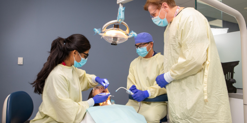 Dental students examine a patient in the clinic.