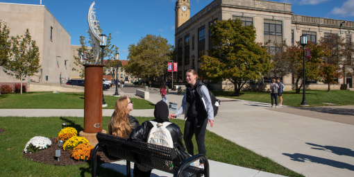 Three students talk outside on campus on a fall day.