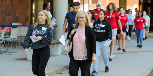 An organized group takes a walking tour of the Detroit Mercy campus with a current student
