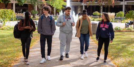 Students walk past the fountain on a fall day.