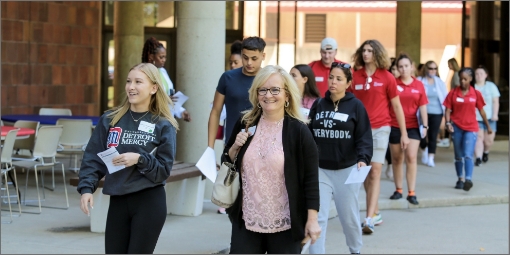 An organized group takes a walking tour of the Detroit Mercy campus with a current student